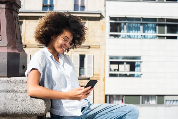 Retrato Sonriente Afroamericano Adolescente Sentado Fuera Mirando Teléfono Celular —  Fotos de Stock