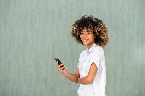 Portrét Usmívající Mladá Afroameričanka Držící Mobilní Telefon Zelené Stěny — Stock fotografie