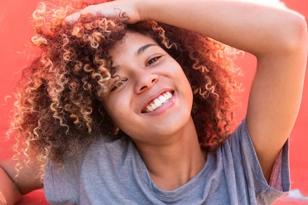 Close up portrait smiling young black woman with hand in afro hair