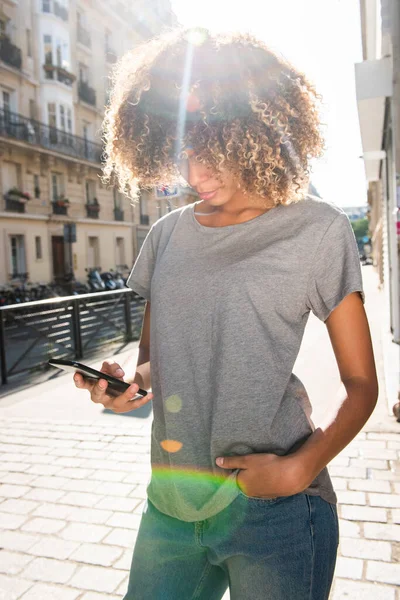 城市街道上看手机的年轻黑人妇女的画像 — 图库照片