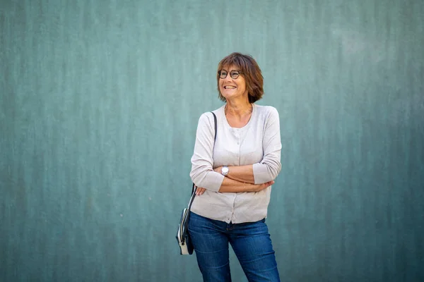 Portret Starszej Kobiety Uśmiechającej Się Torbą Odwracając Wzrok Zielonym Tle — Zdjęcie stockowe