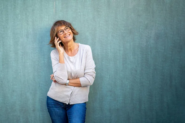 Portrait older woman talking with mobile phone by green background