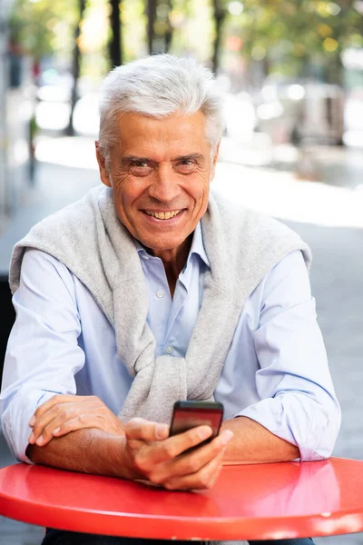 Şehirde Cep Telefonu Tutan Gülümseyen Gri Saçlı Adamın Portresi — Stok fotoğraf