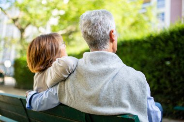 Park bankında oturan yaşlı bir çiftin portresi.