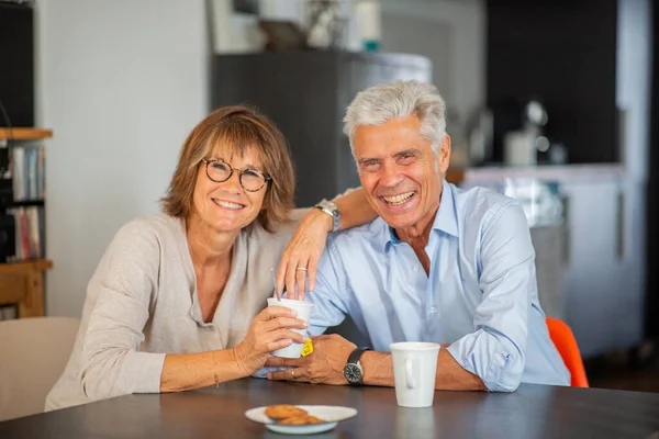 面带微笑的成熟夫妇坐在餐桌边喝茶 — 图库照片