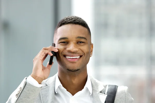 Knappe jonge man die lacht met mobiele telefoon — Stockfoto