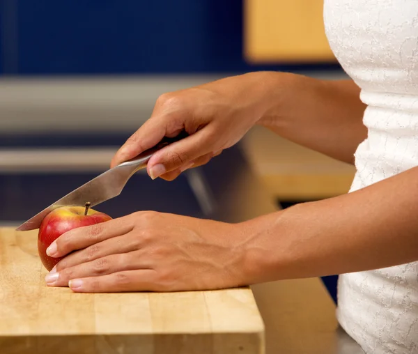Kvinnliga händer som håller skär äpple i köket — Stockfoto