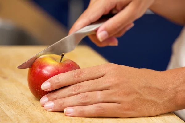 Female hands cutting apple with knife — Stock Photo, Image