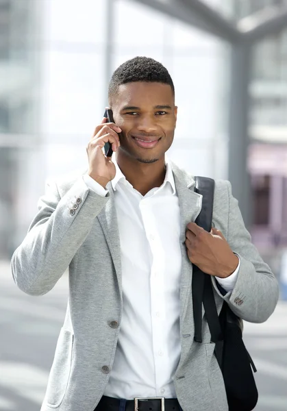 Young black man with bag talking on mobile phone Royalty Free Stock Images