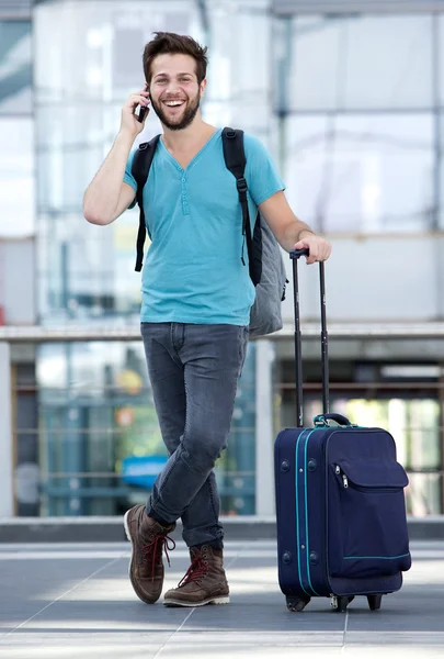 Jonge man die lacht met koffer op luchthaven — Stockfoto