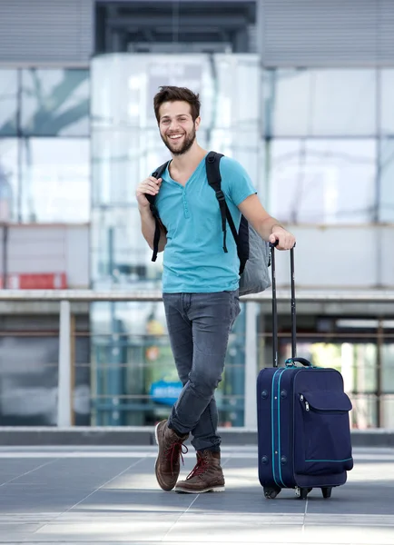 Jonge man die lacht met tassen bij luchthaven — Stockfoto