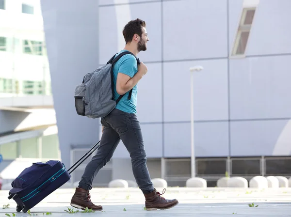 Junger Mann geht mit Koffer ins Freie — Stockfoto