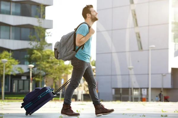 Jeune homme marchant avec valise et sac — Photo