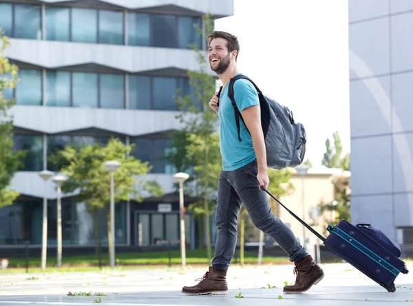 Joven sonriente viajando con maleta y bolso — Foto de Stock