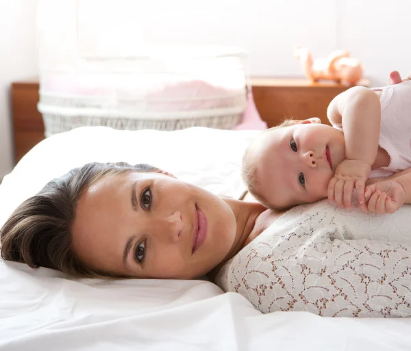 Hermosa madre descanso en la cama con la hija bebé —  Fotos de Stock