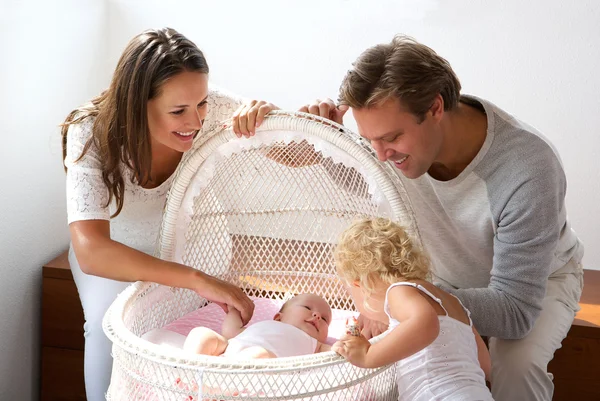 Junge Familie lächelt Neugeborenes im Kinderbett an — Stockfoto