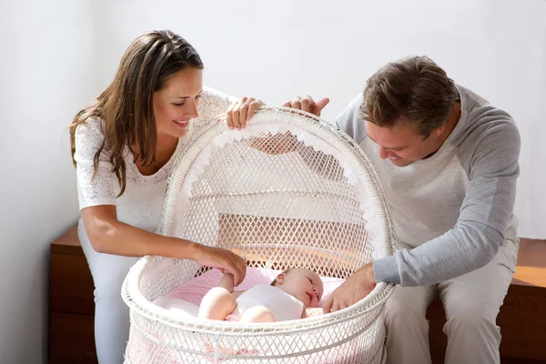 Happy couple smiling with baby in cot — Stock Photo, Image