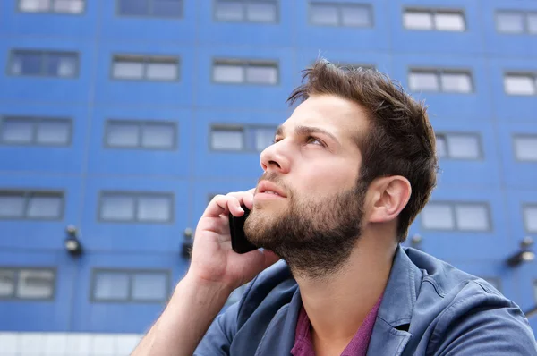 Mladý muž myšlení s mobilním telefonem — Stock fotografie