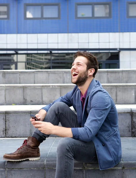 Lächelnder junger Mann per SMS auf Handy — Stockfoto