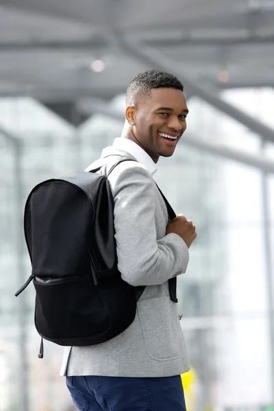 Joven hombre negro sonriendo con el bolso en el aeropuerto — Foto de Stock