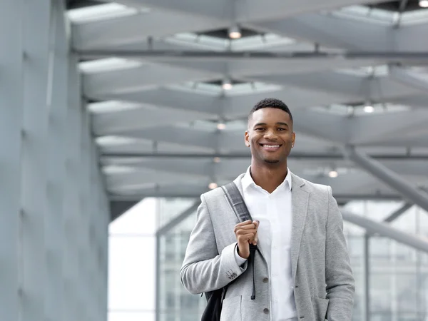 Afroamerikanska mannen leende med väska på flygplatsen — Stockfoto