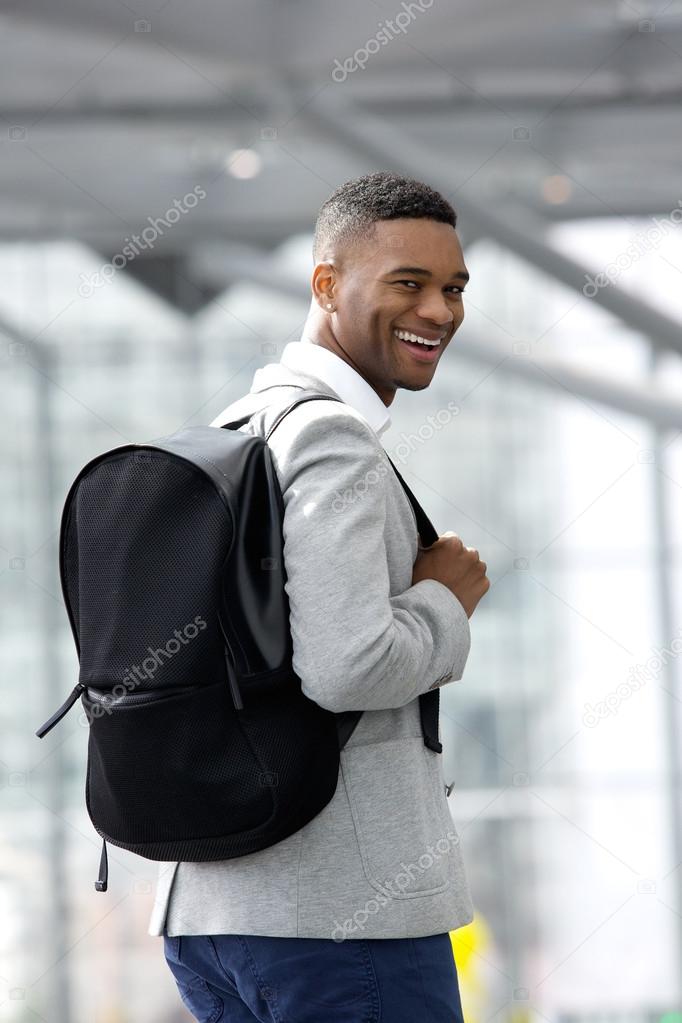 Young black man smiling with bag at airport