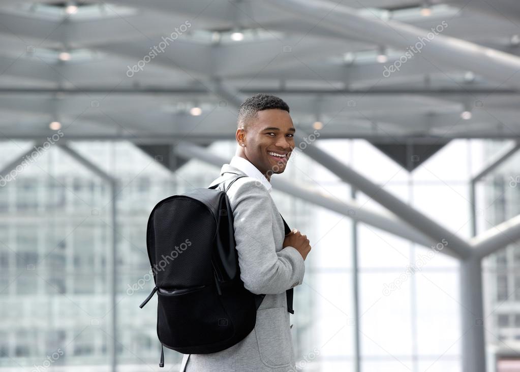 Handsome young man smiling with bag at airport 
