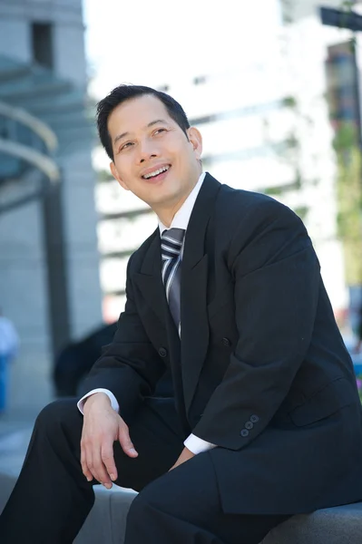 Uomo d'affari sorridente seduto all'aperto — Foto Stock