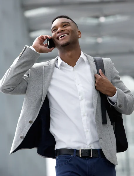Leende ung man går och pratar i mobiltelefon — Stockfoto