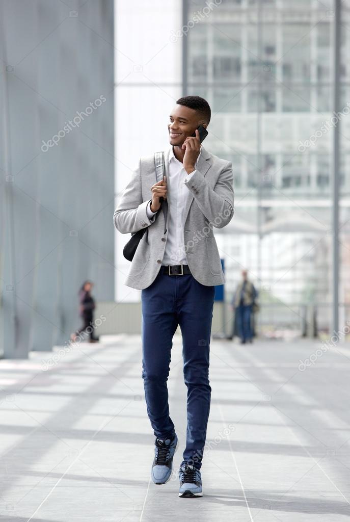 Happy young man walking and talking on mobile phone