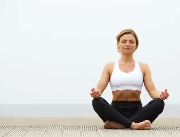 Jonge vrouw zitten buiten in yoga pose — Stockfoto