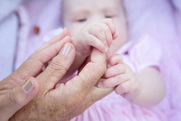 Mormor händer som håller barnet händer — Stockfoto