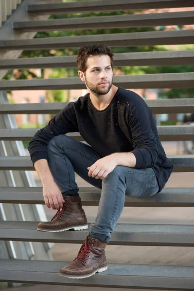Cool guy in black clothing sitting on steps — Stock Photo, Image