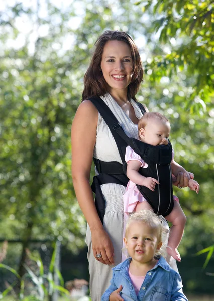 Beautiful mother smiling with two baby daughters — Stock Photo, Image