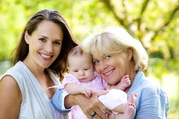 Mãe e avó sorrindo com bebê ao ar livre — Fotografia de Stock