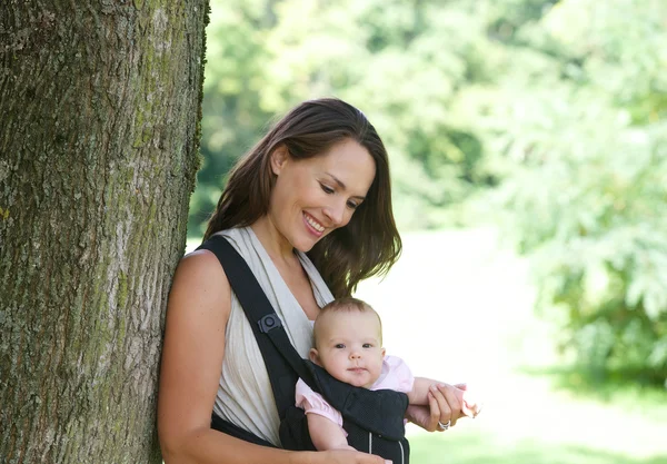 Sonriente madre con lindo bebé en honda — Foto de Stock