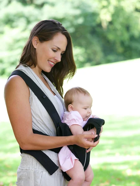 Aantrekkelijke moeder lacht met baby in sling — Stockfoto