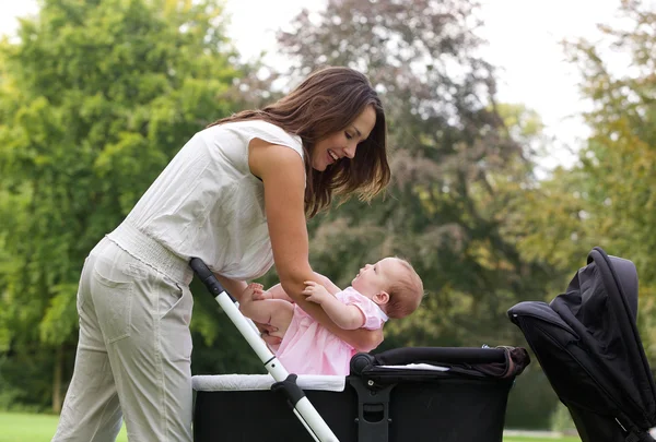 Mamma sätta barnet i barnvagn — Stockfoto