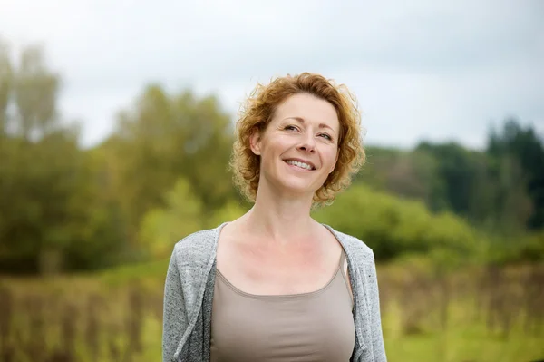 Mooie midden leeftijd vrouw die lacht buitenshuis — Stockfoto