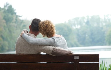 coppia seduta sulla panchina vicino al lago 