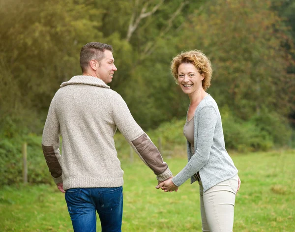 Happy couple holding hands and walking outdoors — Stock Photo, Image