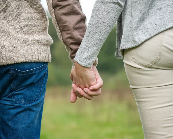 Male and female holding hands outdoors — Stock Photo, Image