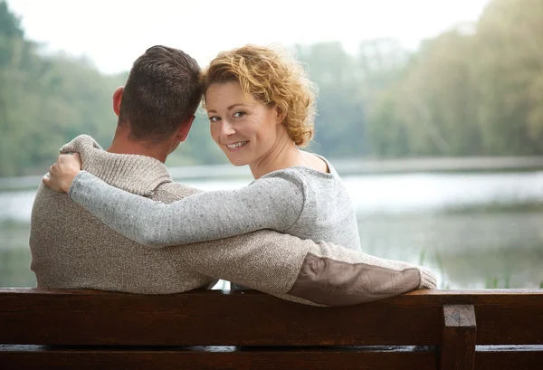 Couple sitting on bench by a lake — Stock Photo, Image