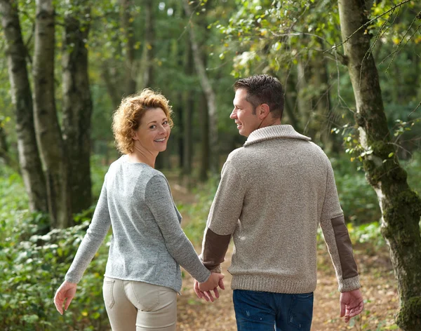 Glückliches Paar hält Händchen und geht im Wald spazieren — Stockfoto