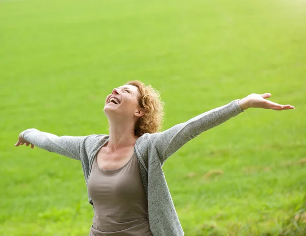 Cheerful older woman smiling with arms outstretched — Stock Photo, Image