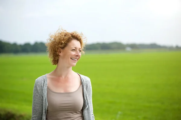 Piękna kobieta uśmiechając się na zewnątrz przez zielonych krajobrazów — Zdjęcie stockowe