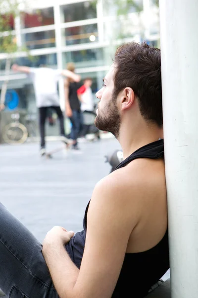 Молодой человек с бородой сидит на улице — стоковое фото