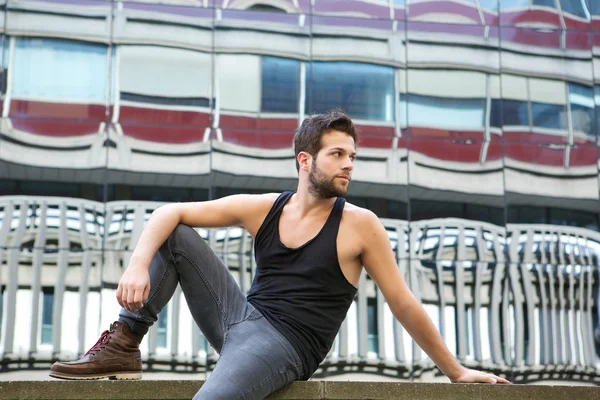 Male fashion model sitting outdoors in urban area — Stock Photo, Image