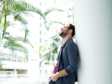 mutlu genç adam parlak binada duvara yaslanmış