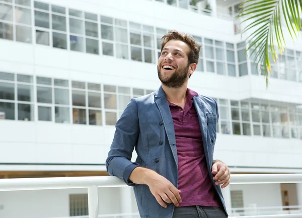 Sorridente giovane uomo con la barba in piedi in edificio bianco — Foto Stock